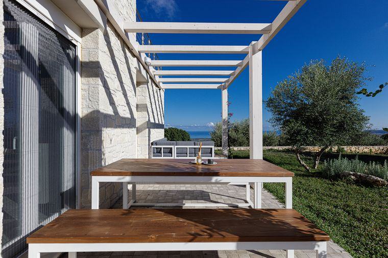 Essplatz unter der Pergola der Villa Eos mit Blick aufs Meer