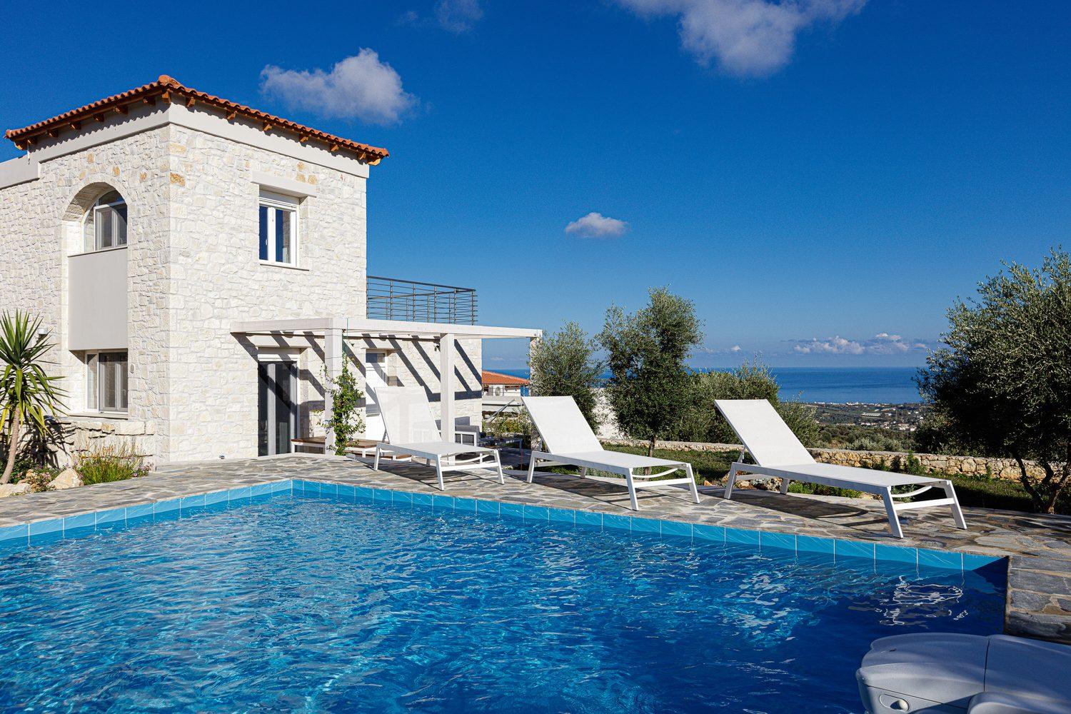 Villa Eos: Natursteinhaus mit langem Pool, Sonnenliegen und Blick über Olivenhaine zum Meer
