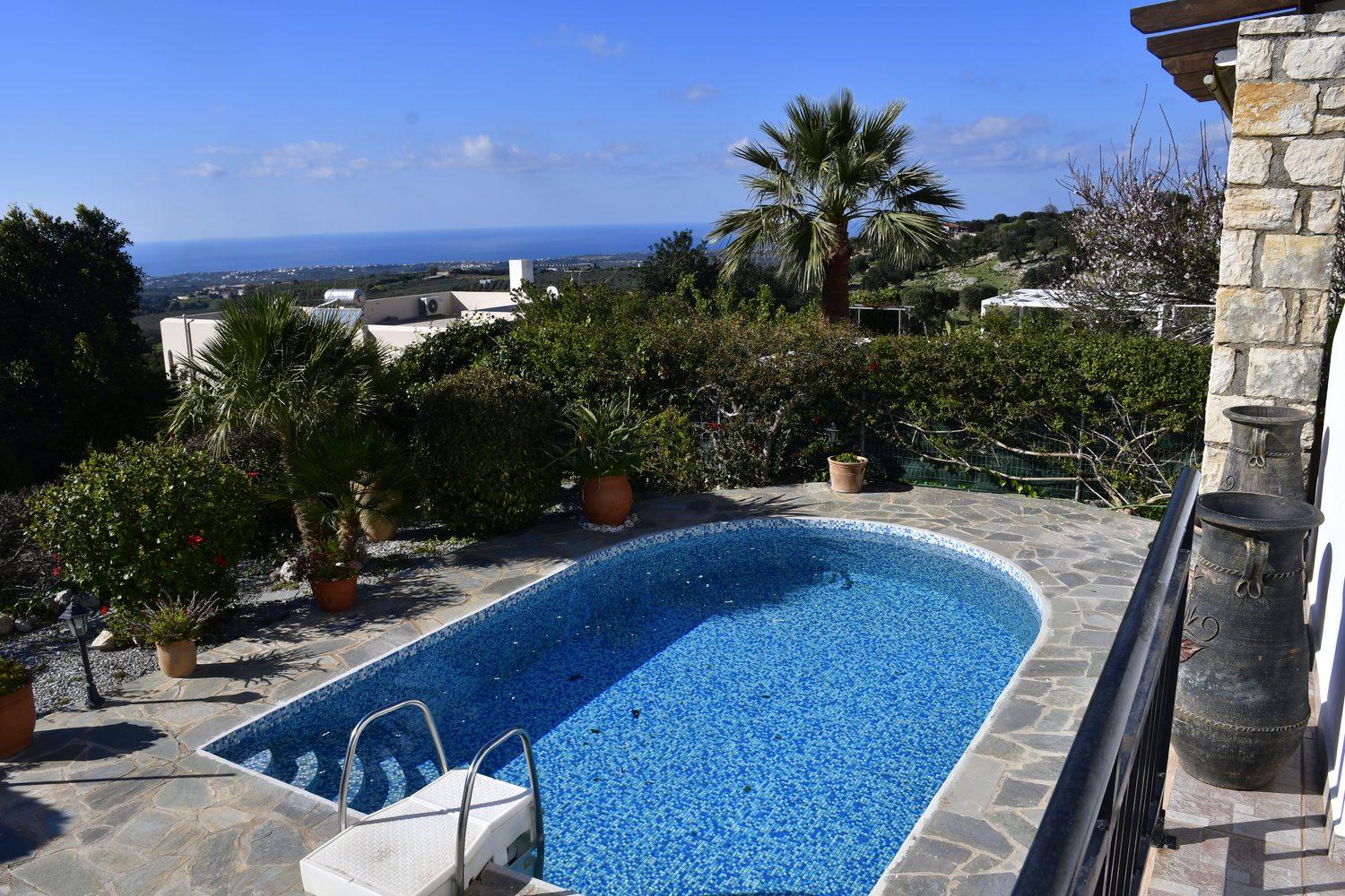 Pool der Villa Mailin mit Palme, Steinmauer und Blick über die Umgebung